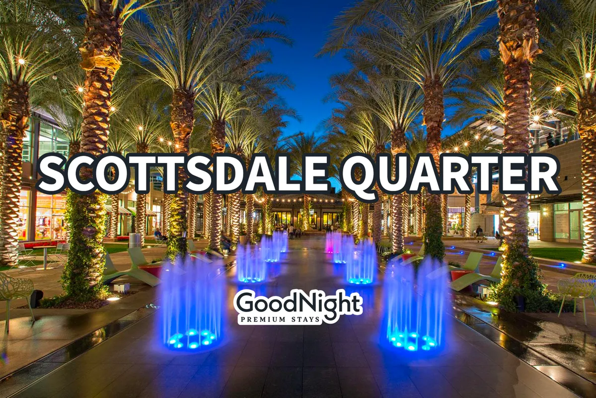 A lively exterior scene featuring colorful water fountains, tall palm trees, and modern architecture. The space is filled with people dining at outdoor cafes, shopping, and enjoying social gatherings, all under a festive atmosphere with vibrant lighting.