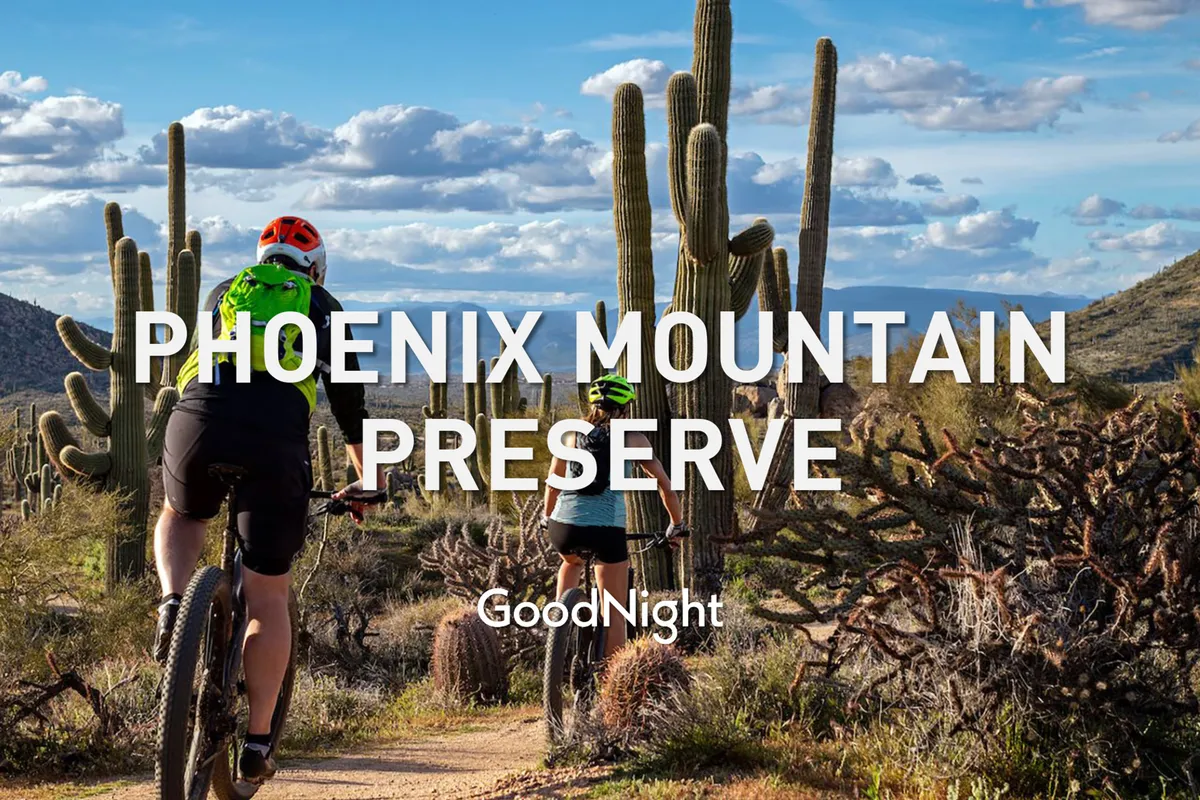 A scenic desert landscape featuring cyclists on a winding trail, surrounded by cacti and mountainous terrain. The image conveys a sense of adventure and access to the outdoors, with an emphasis on active lifestyle and nature.