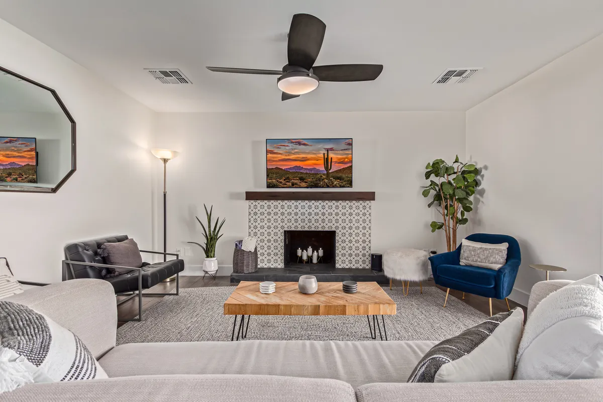 A cozy and contemporary living area with a central coffee table, artwork above the fireplace, a blue chair, and a lush plant. The environment feels welcoming and is suited for both relaxation and informal meetings or creative breaks.